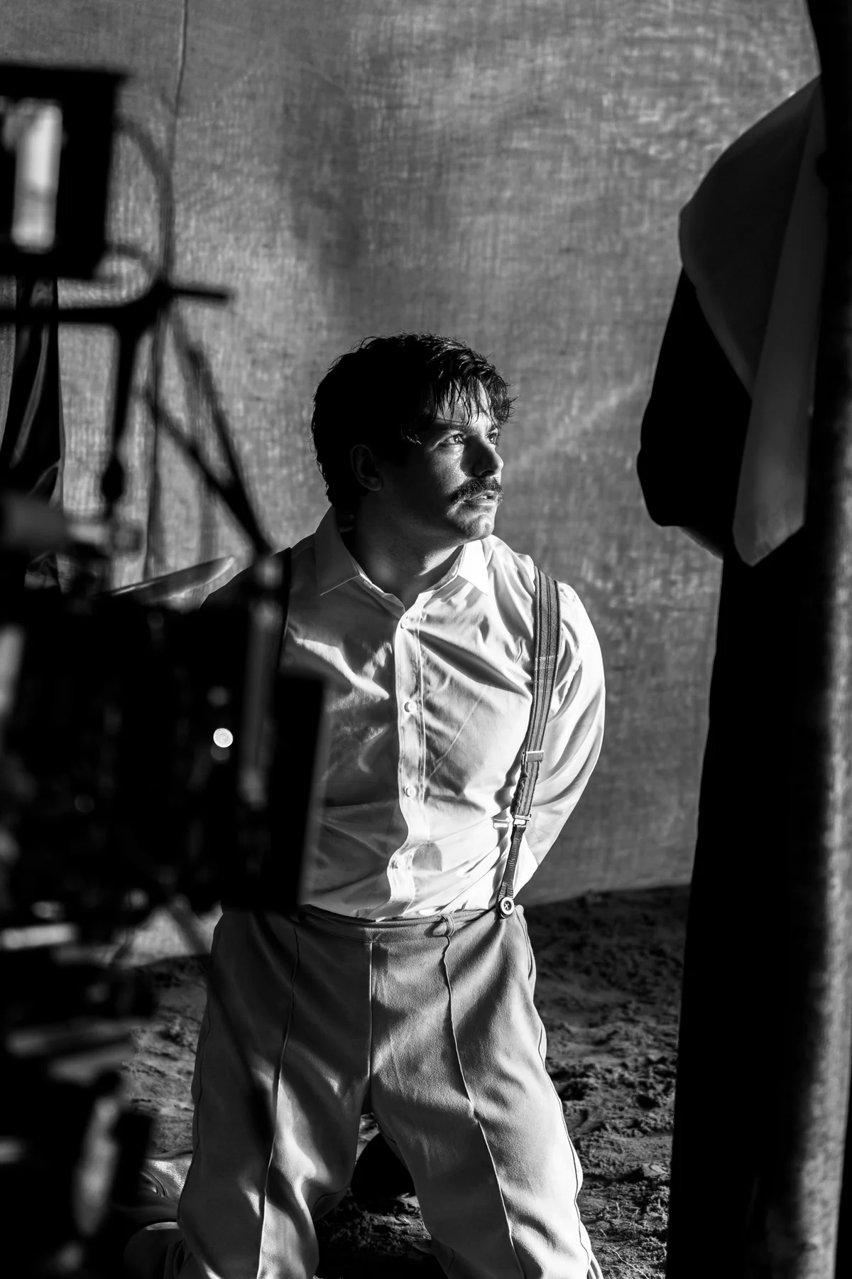 Luke Hunter kneeling in period costume on the Ozmar set, with camera equipment in the foreground