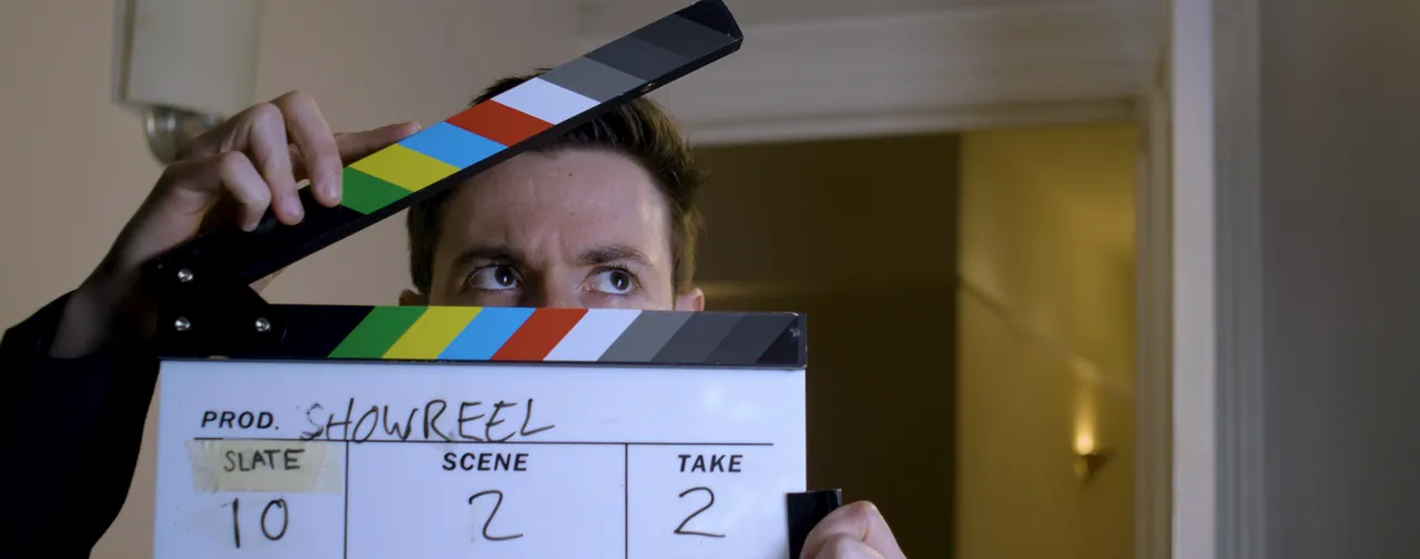 Luke Hunter looking over a colourful clapperboard marked Showreel